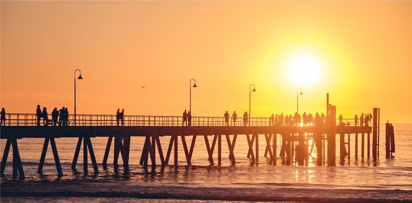 People walking along Glenelg jetty at sunset, Adelaide, South Australia.