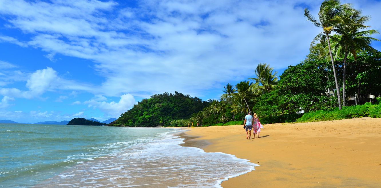 A couple walks on Trinity beach near Cairns in Queensland.