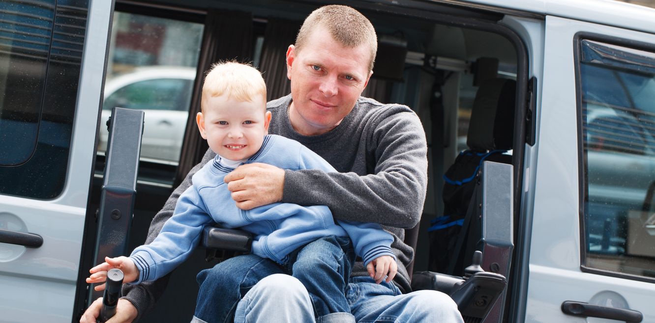 Man and child use a car equipped with a wheelchair lift